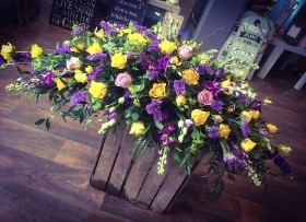 Casket spray in purples and yellow
